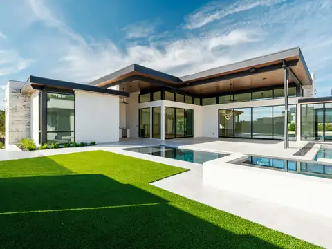 Light gray concrete and tile pool deck around a modern pool and spa beside a white contemporary house