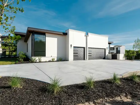 Large smooth concrete driveway in front of a modern white house with two dark garage doors
